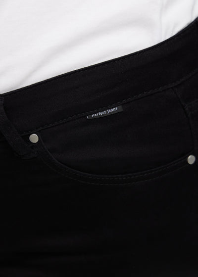 Forlommen på et par sorte jeans, hvor man kan se logoet på en plus-size model.